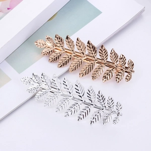 Detailed macro view of metal leaf hair clips in gold and silver with elegant vein texture