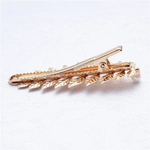 Detailed view of a golden metal leaf hair clip with elegant pearl accent for women