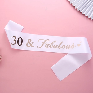 Close-up of a white satin sash with gold 30 & Fabulous text and heart detail