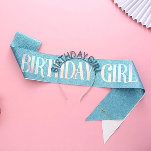 Close-up of blue glitter sash and headband set with BIRTHDAY GIRL text and gold safety pin