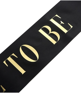 Macro view of black satin sash with metallic gold TO BE lettering for bridal events