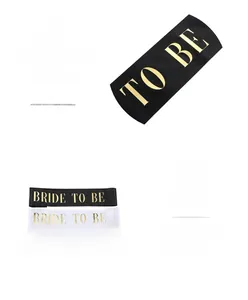 Detail view of silk satin Bride to Be sashes in black, white, and pink with gold foil print