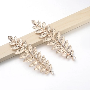 Detail view of golden metal leaf hair clips with white pearl and sparkling rhinestones