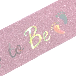 Detail von rosa glitzernder Mommy to Be Schärpe mit Laserschrift und Baby-Fußabdrücken