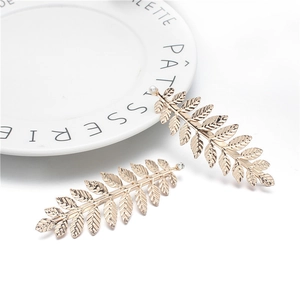 Close-up of golden leaf hair clips with white pearl and rhinestone on a white plate