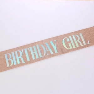 Close-up of glittery rose gold birthday girl sash with holographic text detail