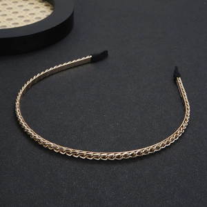 Detail of a thin gold metal headband with chain design and protective black tips