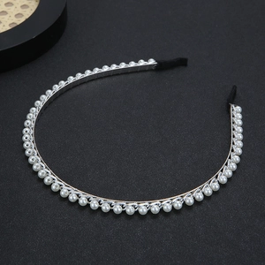 Détail d'un serre-tête en métal argenté avec perles blanches et embouts en tissu noir