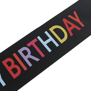 Close-up of rainbow birthday sash with colorful printed text for party decoration