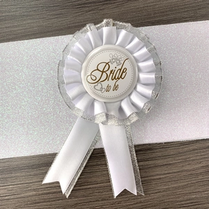 Elegant white lace Bride to Be badge with silver glitter accents on wooden background