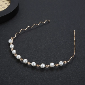 Elegant gold metal headband with white pearls and sparkling rhinestones on black background