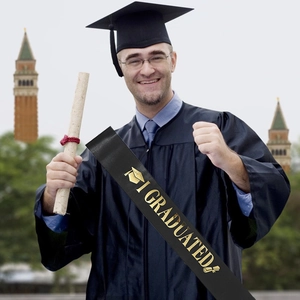 Detail of black satin graduation sash with gold I GRADUATED text and academic icons