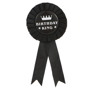 Détail d'un badge d'anniversaire en soie noire avec couronne et ruban plissé élégant