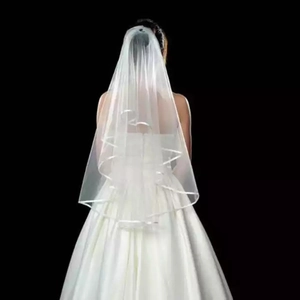 Detail of a two-layer bridal veil with satin edges shown on a white wedding dress