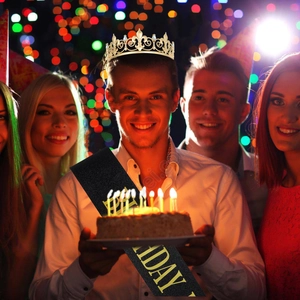 Golden crown and black birthday king sash set with sparkling festive bokeh background