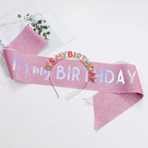 Dettaglio fascia rosa glitterata con testo olografico e cerchietto di compleanno abbinato