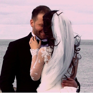 Elegant white two-layer bridal veil with comb shown on bride during seaside wedding shoot