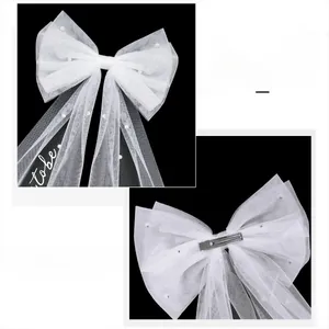 Détail d'un nœud de mariée blanc avec voile en maille perles et texte Bride to be