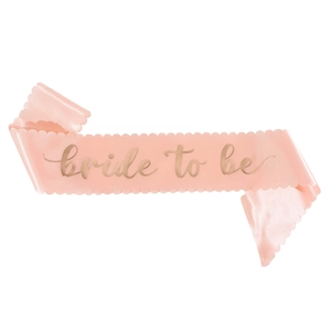 Close-up of light pink satin sash with scalloped edges and gold Bride To Be lettering