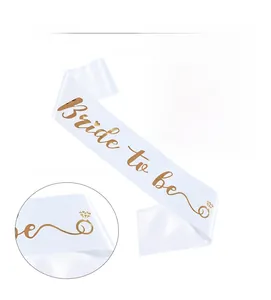 Detail of white satin sash with gold foil Bride to be text and heart ring pattern