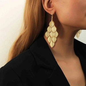 Gros plan de boucles d'oreilles pendantes feuilles dorées multicouches sur un modèle