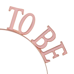 Close-up of rose gold MUMMY TO BE headband with pink enamel lettering for party