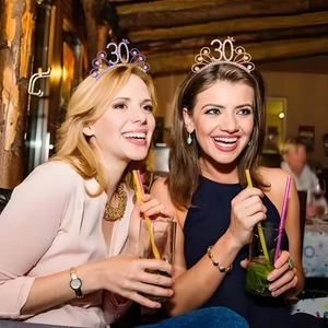 Gros plan de tiares d'anniversaire 30 ans en strass portées par des femmes en fête