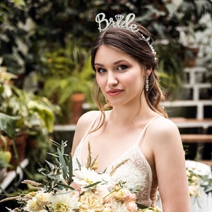 Detailed view of rhinestone Bride headband worn by model with lace dress and bridal bouquet