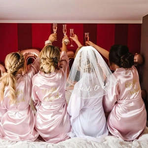 Detail of pink satin bridesmaid robe with gold text and pearl bride to be veil