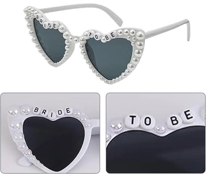 Close-up of heart-shaped sunglasses with pearls, rhinestones and BRIDE TO BE letters