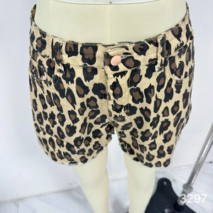 Detail of high waisted leopard print denim shorts with raw hem and metallic button