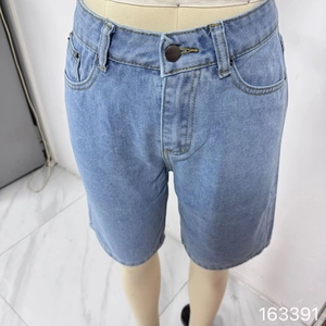 Detalle de pantalones cortos vaqueros azul claro con pespuntes dorados y botón metálico