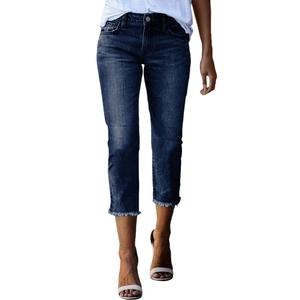Detail shot of slim-fit dark blue jeans featuring frayed hems and vintage whisker washing