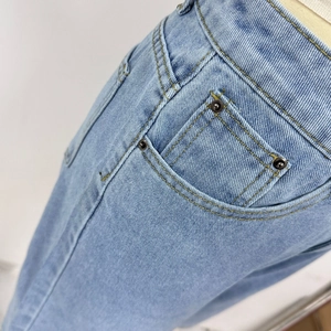 Detalle de costura doble y remaches metálicos en pantalones cortos de mezclilla retro