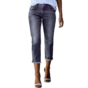 Detail view of dark grey washed denim pants with stylish frayed raw hem and slim fit cut