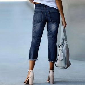 Detailed back view of slim fit dark blue cropped jeans with raw hem and wash effect