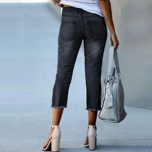 Detailed back view of grey washed denim cropped jeans featuring a stylish frayed hem