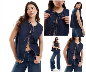 Detail of dark blue washed denim vest with triple lace-up front closure and clean stitching