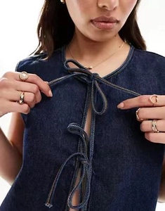 Detailed close-up of dark blue denim vest with lace-up front and V-neckline texture