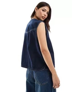 Detail view of dark blue sleeveless denim vest with white contrast stitching and side slits