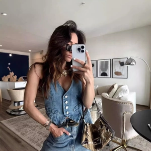 Détail du gilet en jean bleu avec boutons blancs et col en V ajusté dans un salon