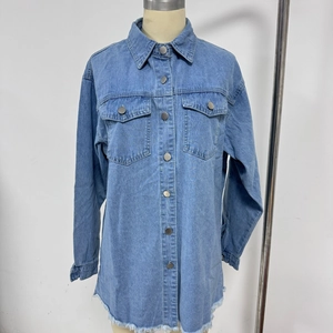 Detail of blue denim shirt featuring metal buttons, chest pockets and raw fringe hem
