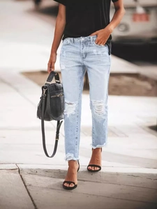 Women's slim fit distressed denim jeans in light blue wash with ripped knees and raw hems