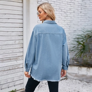 Detail of light blue denim jacket featuring raw hem edge and washed cotton texture