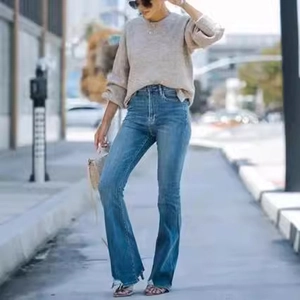 Detail of high-waisted flared jeans with distressed hems and vintage washed denim texture