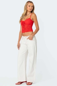 Detail of white wide leg jeans with red contrast stitching and red lace camisole top
