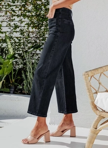 Side view of high waisted black wide leg jeans with visible side patch pocket detail
