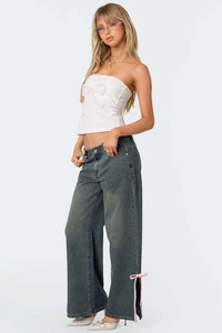 Detail of wide leg dark grey denim pants with side slit and pink ribbon bow accents