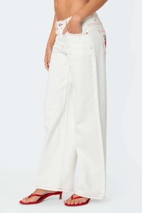Detail of white wide-leg jeans with red contrast stitching and embroidered back pocket