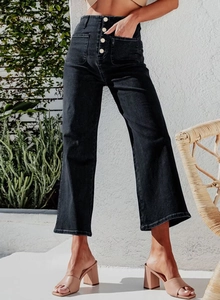 Detail of high waisted black wide-leg denim jeans with gold button fly and cargo pockets
